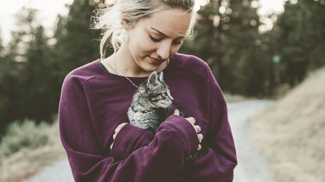 Kuvituskuva: Nainen pitää kissanpentua sylissä ulkona.