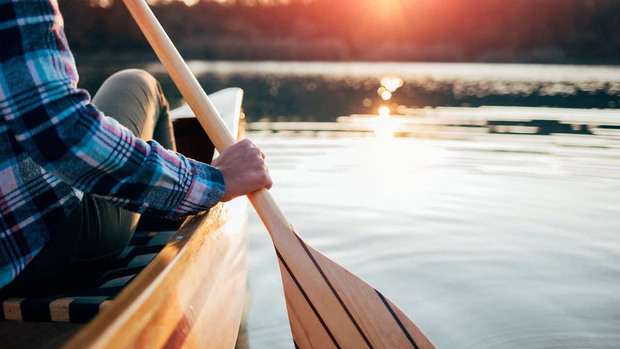 Kuvituskuva: Mies soutamassa veneellä auringonlaskussa.