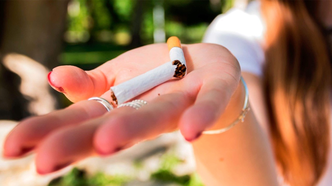 Kuvituskuva: Halkaistu savuke naisen kämmenellä.